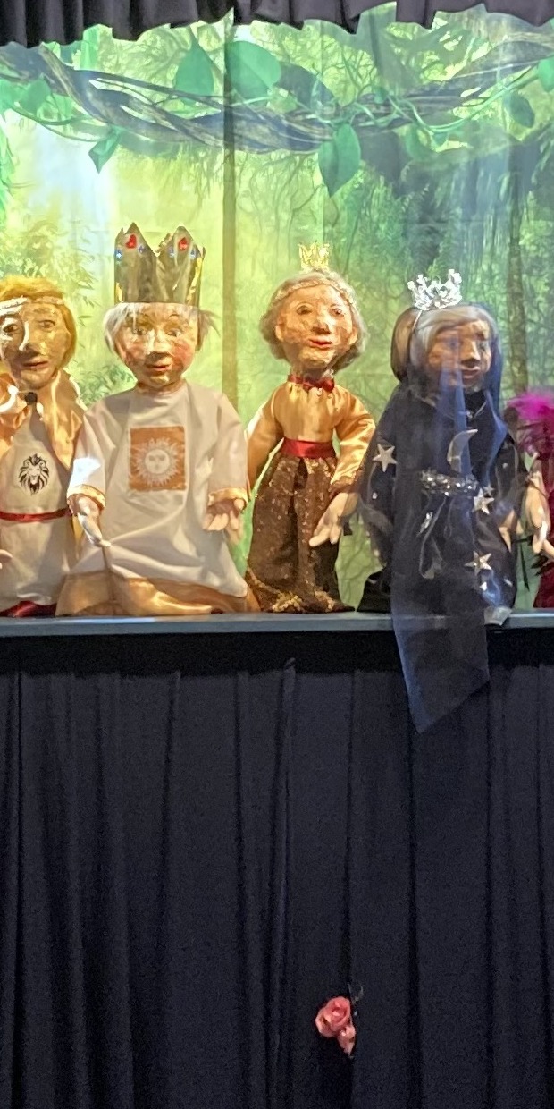 Sieben Handpuppen des Teatro La PeCoMo in Reih und Glied vor der grünen Kulisse der Puppenbühne